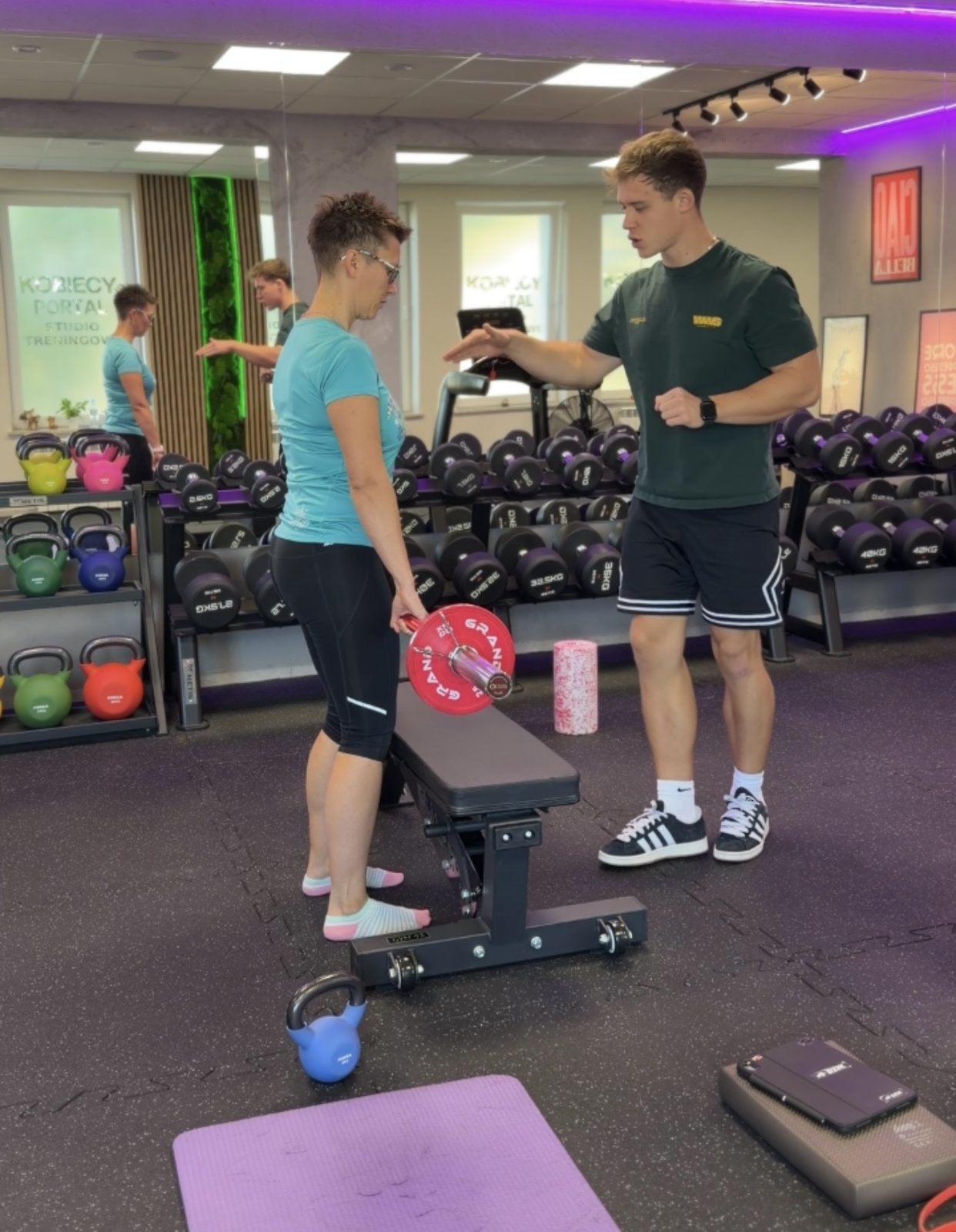 Trener prowadzi klientkę przez trening w studiu